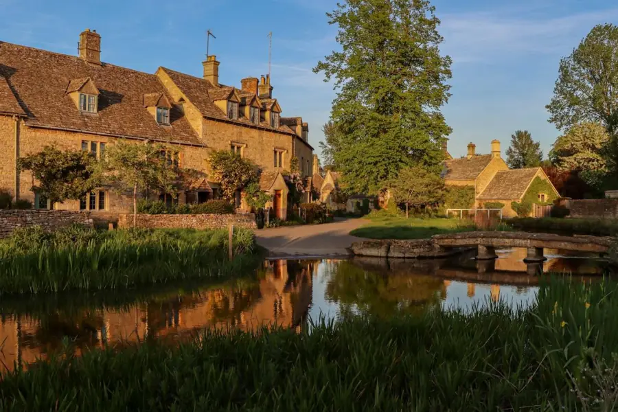 Stone cottages reflected in a river at sunset